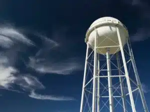 Overflowing water tank outside a New Zealand home with water flowing from the overflow pipe due to a faulty float valve