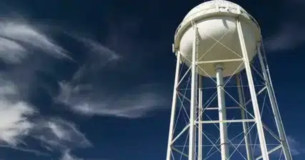 Overflowing water tank outside a New Zealand home with water flowing from the overflow pipe due to a faulty float valve